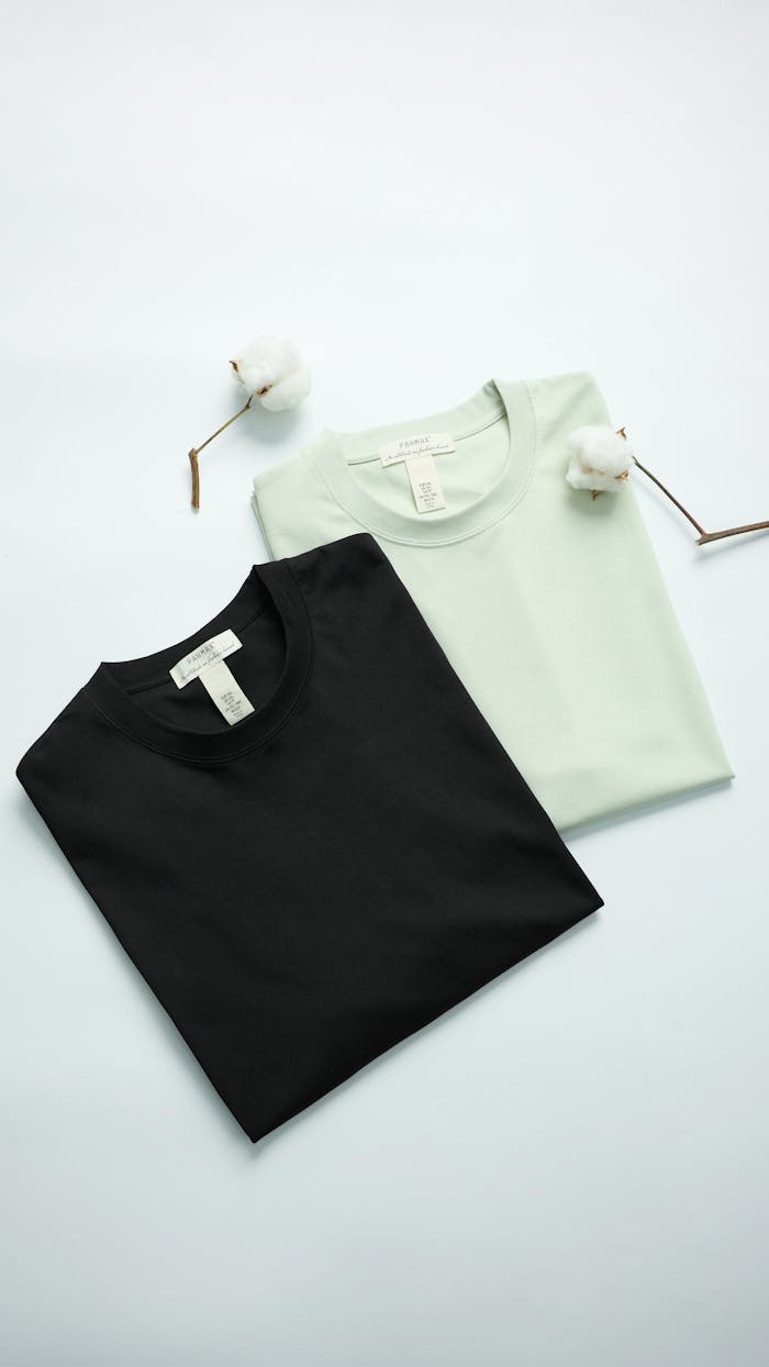 The Art of Drawing Readers In: Your attractive post title goes here Two folded t-shirts in black and mint with cotton flowers on light background.